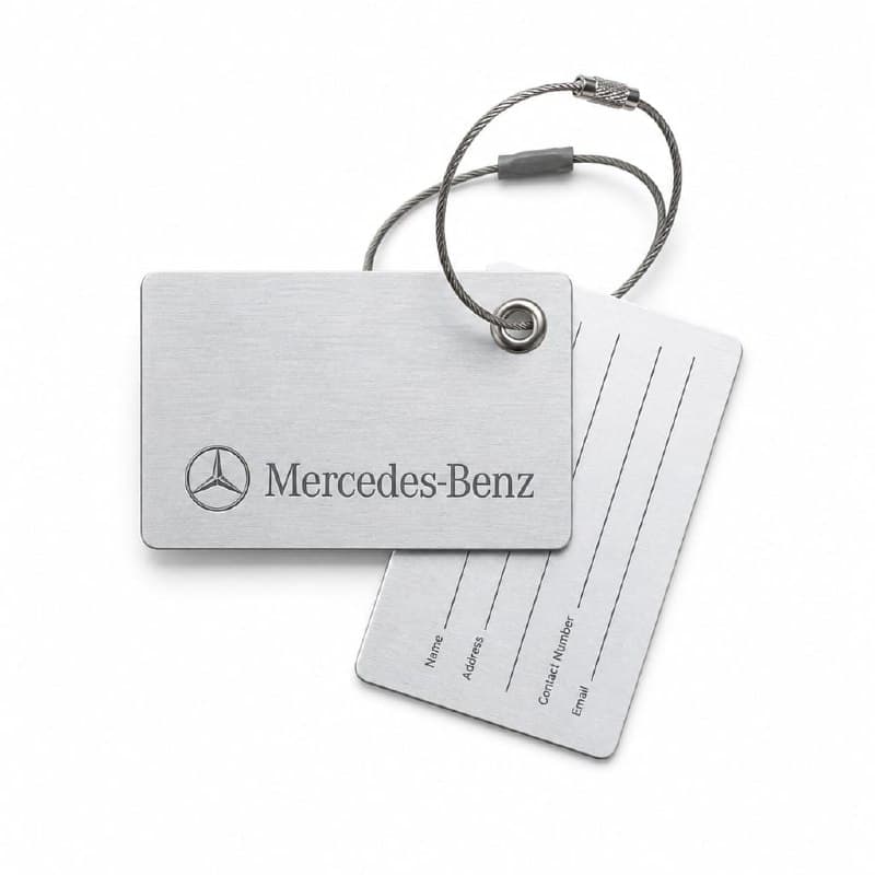 Brushed silver machined aluminium Mercedes-Benz luggage tag with etched three-pointed star and word-mark, finished with a steel wire loop — designed and made by Sense2 for Mercedes-Benz.